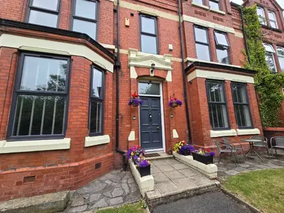 a brick house with a blue door and purple flowers at Victorian Renovation Room 5 in Liverpool