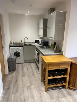 a kitchen with a stove and a sink and a table at Lovely, Sleeps 8, Cafe Bars, Central Formby in Formby