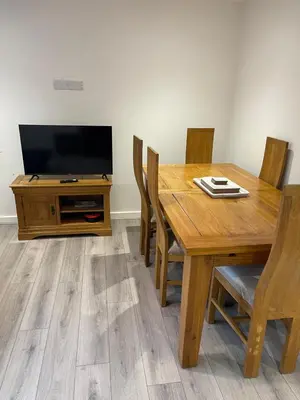 a dining room with a wooden table and a flat screen tv at Lovely, Sleeps 8, Cafe Bars, Central Formby in Formby