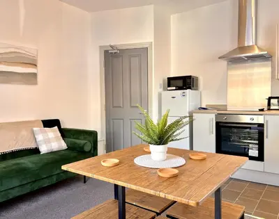 a living room with a table and a green couch at Spare Property Sasco in Blackpool