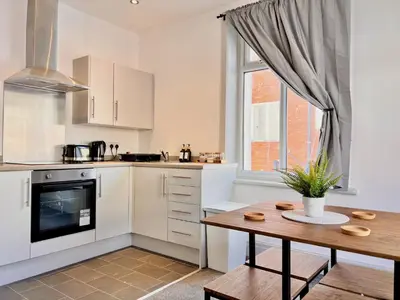 a kitchen with white cabinets and a wooden table at Spare Property Sasco in Blackpool