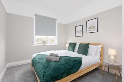a bedroom with a large bed with green pillows at Charles Alexander Short Stay - Ansdell House in Blackpool