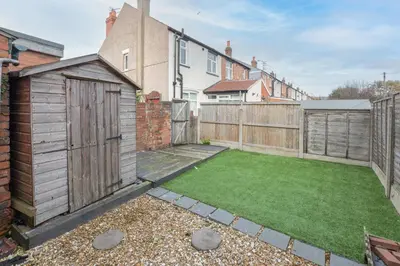a garden with a wooden fence and a small lawn at Charles Alexander Short Stay - Ansdell House in Blackpool