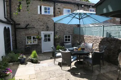 a patio with a table with a blue umbrella at Number 10 in Whalley