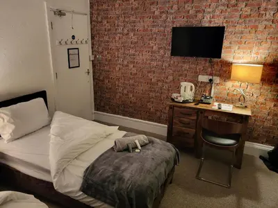 a bedroom with a bed and a desk with a television at Jubilee pub in Litherland