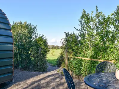 a table and chairs in a garden with a fence at Privet Pod - Uk41394 in Westhead