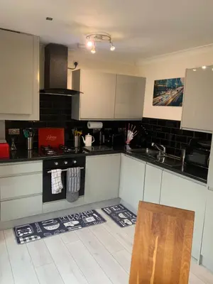 a kitchen with white and black cabinets and a table at Modern 2 bed apartment in Wallasey