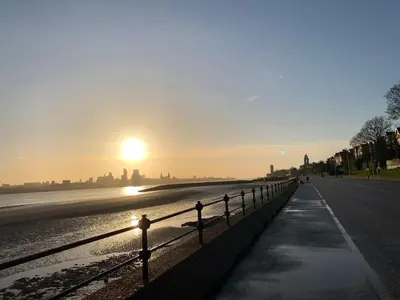 a sunset over a road with a fence on the side at Modern 2 bed apartment in Wallasey