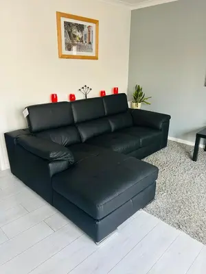 a black leather couch in a living room with red candles at Modern 2 bed apartment in Wallasey