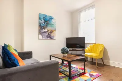 a living room with a couch and a table and a tv at 3-bedroom Home in Liverpool L15 with FREE Parking in Liverpool