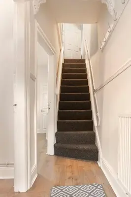 a hallway with stairs in a house with a rug at 3-bedroom Home in Liverpool L15 with FREE Parking in Liverpool