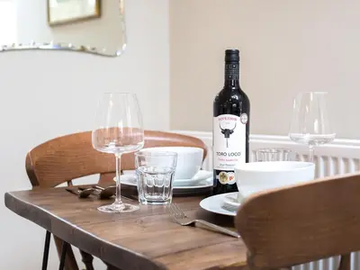 a bottle of wine sitting on a wooden table with glasses at Methera Cottage - Uk41487 in Spark Bridge