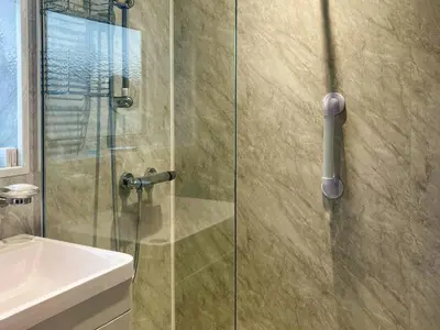 a shower with a glass door next to a sink at The Bay Cottage in Thornton