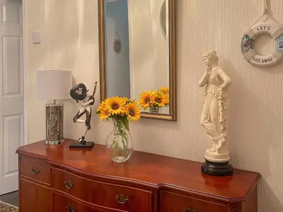 a dresser with a vase of flowers and a statue on it at The Bay Cottage in Thornton