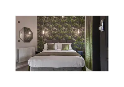 a bedroom with a large bed with a green wallpaper at Home at 2 Tancred Road Anfield in Liverpool