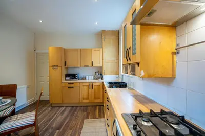 a kitchen with wooden cabinets and a stove top oven at Chestnut Heritage,- Large & Cheerful 5 bedroom house with free parking in Liverpool