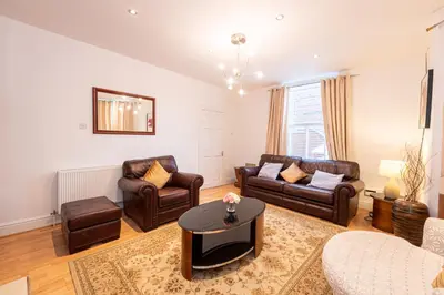 a living room with leather furniture and a table at Chestnut Heritage,- Large & Cheerful 5 bedroom house with free parking in Liverpool