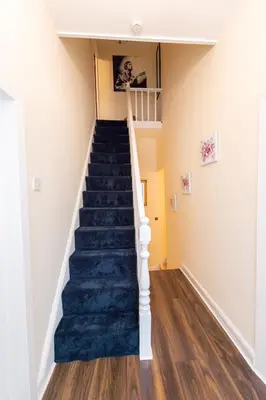 a staircase in a house with a blue carpet at Chestnut Heritage,- Large & Cheerful 5 bedroom house with free parking in Liverpool