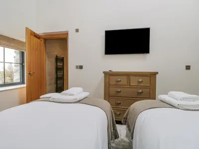 a bedroom with two beds and a tv on the wall at Old Stable in Ulverston
