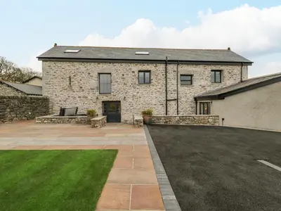 a stone house with a patio and a yard at Old Stable in Ulverston