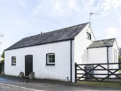 a small white building with a black roof at Guards Cottage in Ulverston