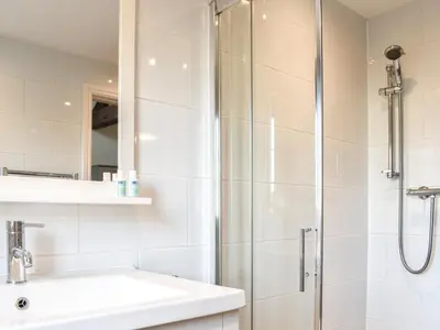 a white bathroom with a shower and a sink at Guards Cottage in Ulverston