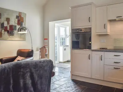 a kitchen with white cabinets and a table and a chair at Guards Cottage in Ulverston