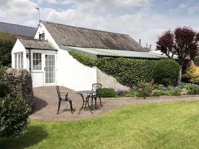 a table and chairs in front of a house at Guards Cottage in Ulverston