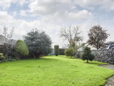 a large yard with a stone wall and green grass at Guards Cottage in Ulverston