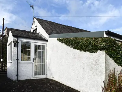 a white house with a window and ivy at Guards Cottage in Ulverston