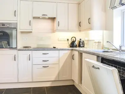 a kitchen with white cabinets and a sink at Guards Cottage in Ulverston