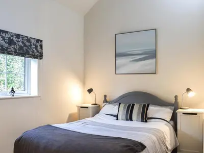 a bedroom with a bed and two lamps and a window at Guards Cottage in Ulverston