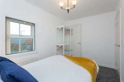 a white bedroom with a bed and a window at Great Park Townhouse in Preston