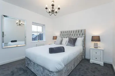 a bedroom with a large white bed and a mirror at Great Park Townhouse in Preston