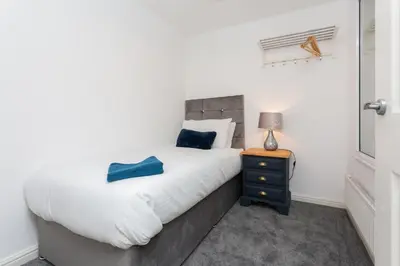 a bedroom with a bed and a night stand with a lamp at Great Park Townhouse in Preston
