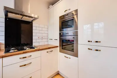 a kitchen with white cabinets and stainless steel appliances at Cosy 2 Bedroom Home in Wigan in Wigan