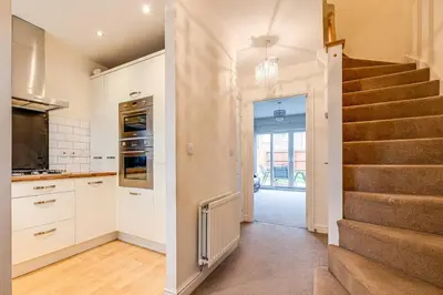 a kitchen with a staircase and a kitchen with white cabinets at Cosy 2 Bedroom Home in Wigan in Wigan