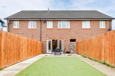a brick house with a fence in front of it at Cosy 2 Bedroom Home in Wigan in Wigan