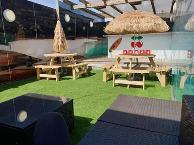a room with two picnic tables and a straw umbrella at City CTR Penthouse - rooftop bar, sleeps 19 in Liverpool