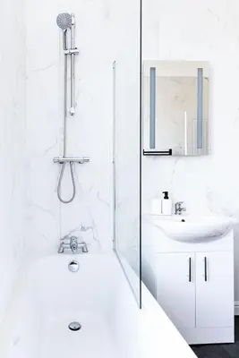 a white bathroom with a shower and a sink at Warwick West in Barrow in Furness