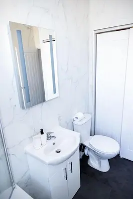 a white bathroom with a toilet and a sink at Warwick West in Barrow in Furness