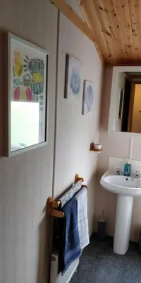 a bathroom with a sink and a mirror and a towel at Lake View Lodge in Millom
