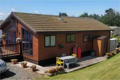 a small house with a table and chairs in front of it at Lake View Lodge in Millom