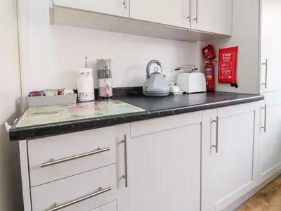 a kitchen with white cabinets and a black counter top at Bungalow by the Sea in Cleveleys
