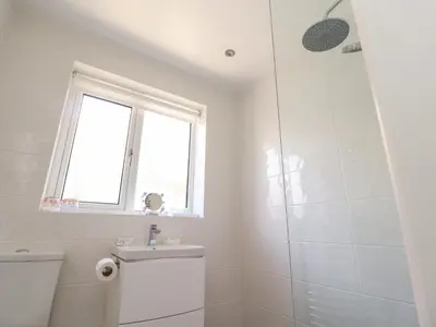 a bathroom with a shower and a toilet and a window at Bungalow by the Sea in Cleveleys