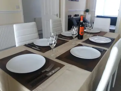 a table with white plates and wine glasses on it at Home from Home near LFC & train station in Liverpool