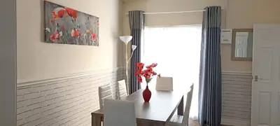 a dining room table with a vase of red flowers on it at Home from Home near LFC & train station in Liverpool