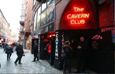 a group of people standing outside of a cavern club at Home from Home near LFC & train station in Liverpool