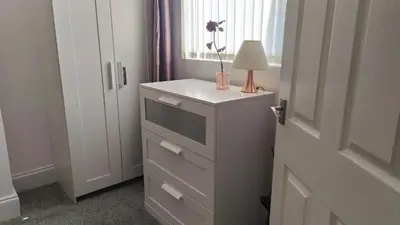 a room with a dresser with a lamp and a window at Home from Home near LFC & train station in Liverpool