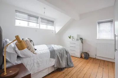 a white bedroom with a bed and a wooden floor at Charles Alexander Short Stay - Hove Suite in Lytham St Annes